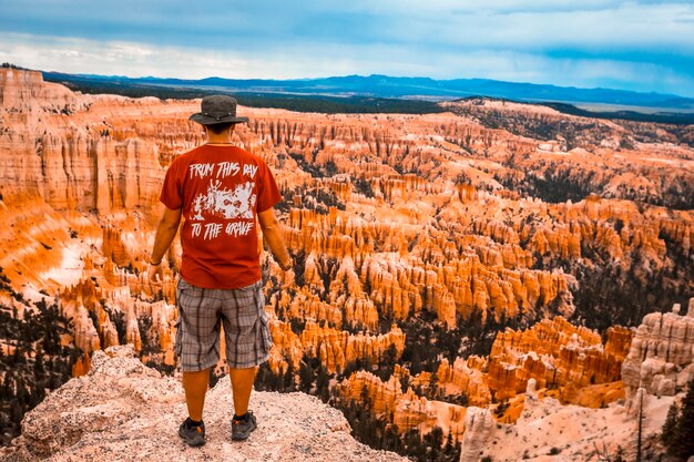 A young man with a red shirt looking at the national park from Bryce Point