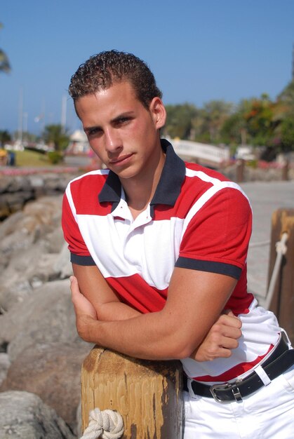 Photo young man with sailor look in a coastal area between sailboats