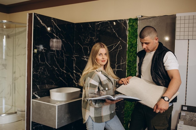 Young man with sales woman choosing tiles at building market