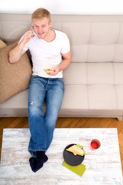 Young man with a Sandwich on the Sofa