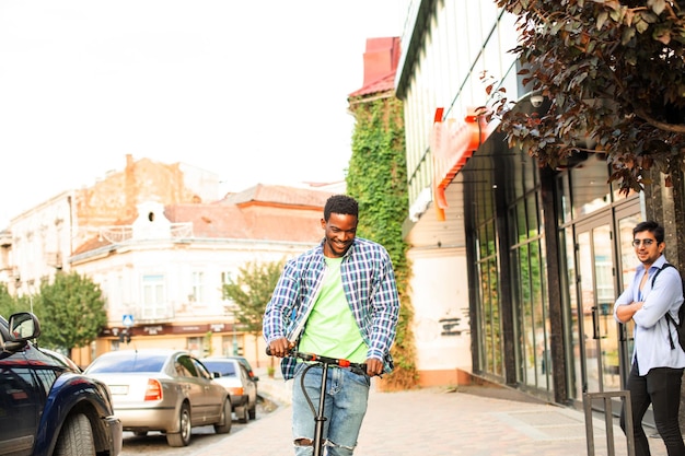 The young man with a scooter is posing in the city