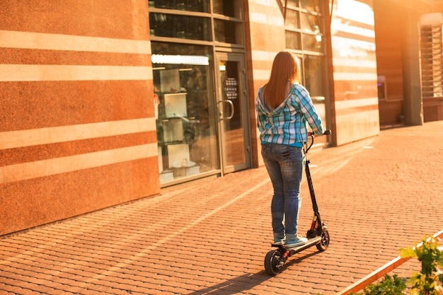 The young man with a scooter is posing in the city