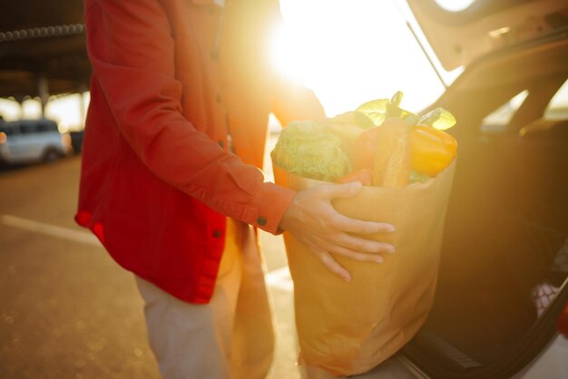 Photo young man with shopping bag full of vegetables near the car healthy lifestyle