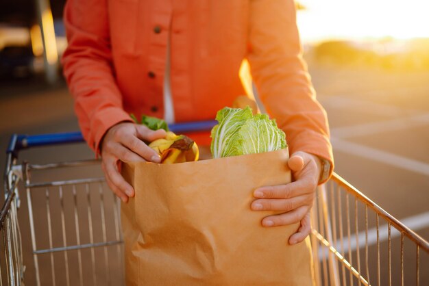 Молодой человек с сумкой, полной овощей возле машины Здоровый образ жизни