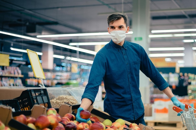 Young man with a shopping cart picking apples. security concept