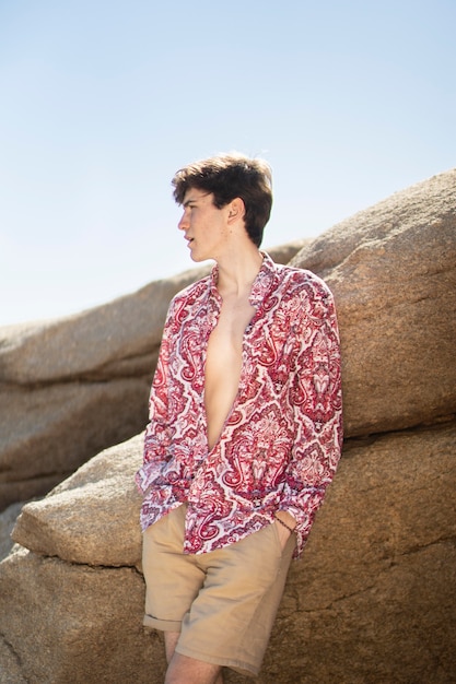 Young man with short and flower shirt among rocks
