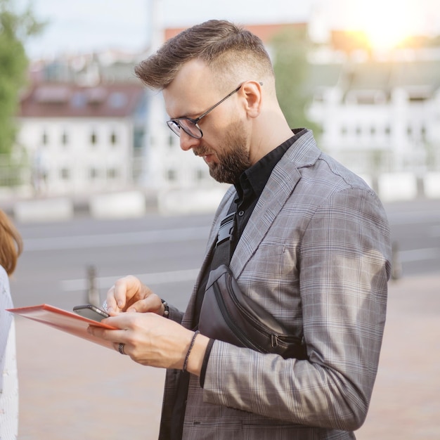 観光客のグループの中に立っているスマートフォンを持つ若者