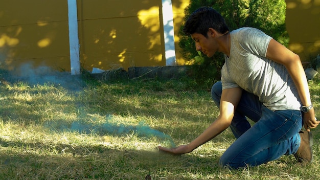 Молодой человек с дымом на коленях на поле