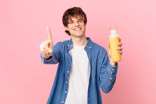 Young man with a smoothy smiling and looking friendly, showing number one