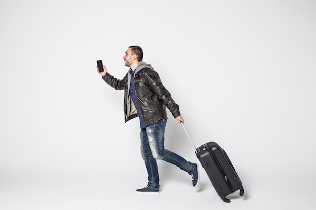 Young man with suitcase running on white background