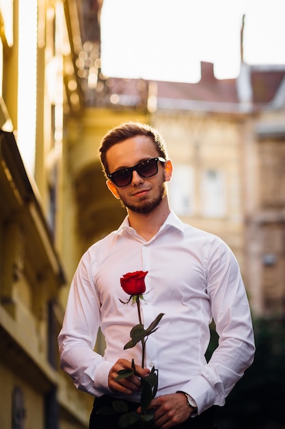 Young man with sunglasses in a white shirt holding a beautiful r