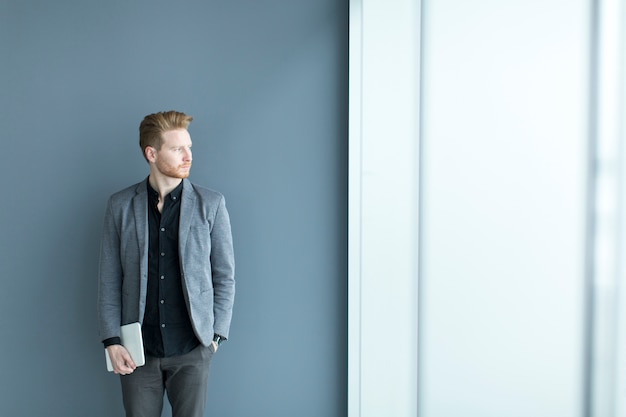 Young man with tablet by the wall