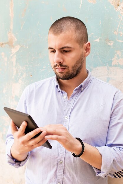 Young man with tablet by the wall