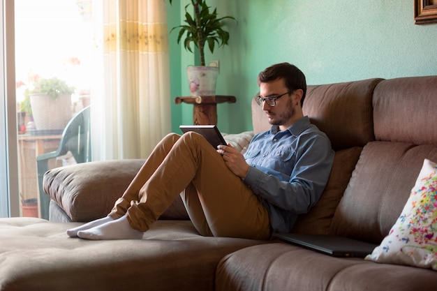 Young man with tablet on sofa at home