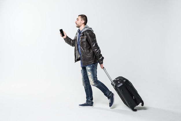 Young man with travel suitcase walking isolated over white background