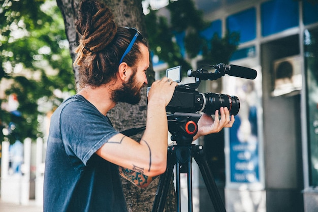 young man with video camera by tree trunk