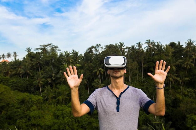 Young man with VR glasses in the tropical forest