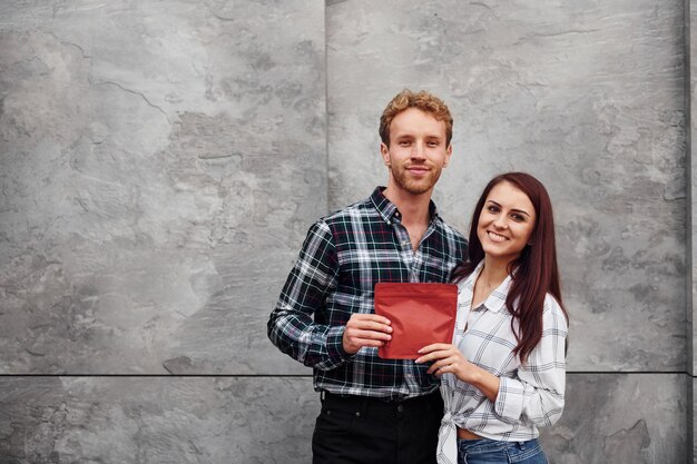 Young man with woman standing together and holding red package of coffee