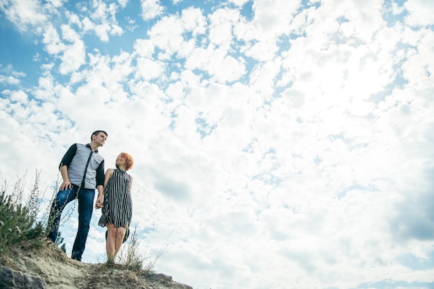 Young man with woman stands on the hill and looks each other