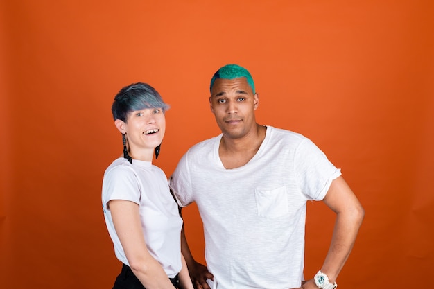 Young man and woman in casual white on orange wall happy and positive emotions