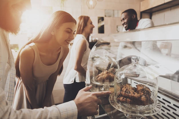 Il giovane e la donna scelgono le pasticcerie in un caffè