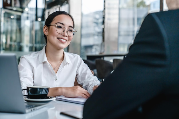 Young man and woman discussing work over a cup of coffee sitting at business center cafe