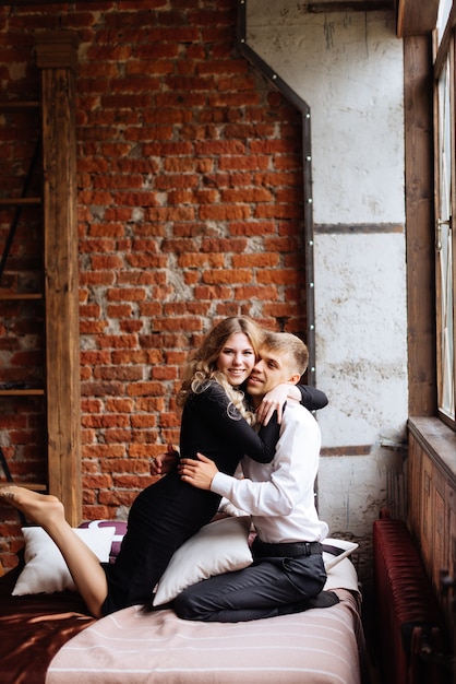 A young man and a woman embrace in a loft-style interior