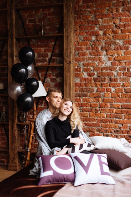 A young man and a woman embrace in a loft-style interior