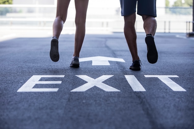 Young man and woman jogging together on street with exit sign