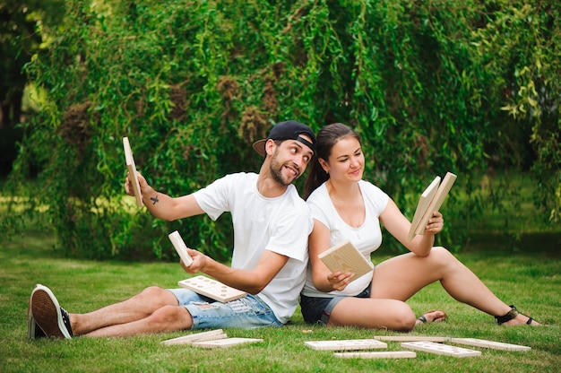 Young man and woman playing giant dominoes in the park on the\
grass.