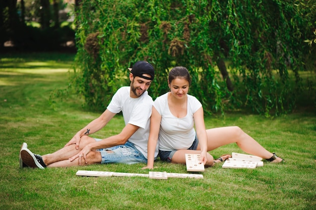 Young man and woman playing giant dominoes in the park on the\
grass.