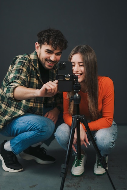 A young man and woman recording a dancing challenge video with their mobile phone on a tripod Modern gen z lifestyle