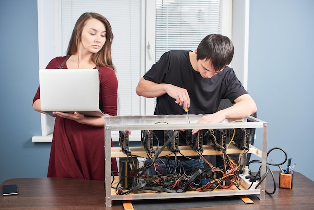 Young man and woman setting up video card farm for cryptocurrency mining