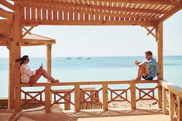 Young man and woman sitting on the beach of the sea Conception of vacation