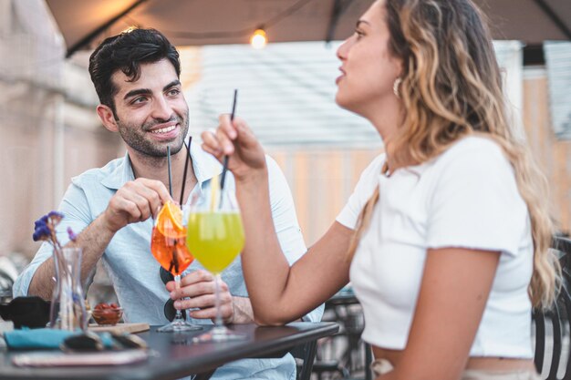 Young man and woman sitting at restaurant drinking cocktails