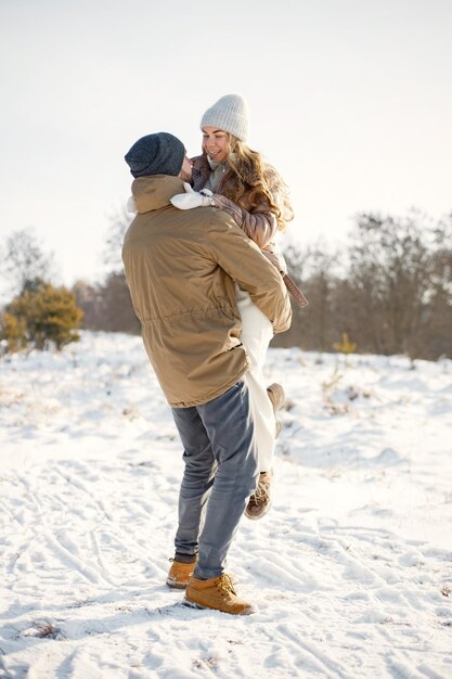 Young man and woman spending time together at winter day and hugging