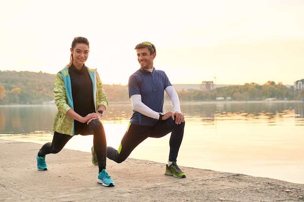 Young man and woman stretching before running