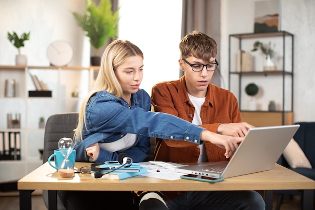 Photo young man and woman using laptop sitting at the table and studying together