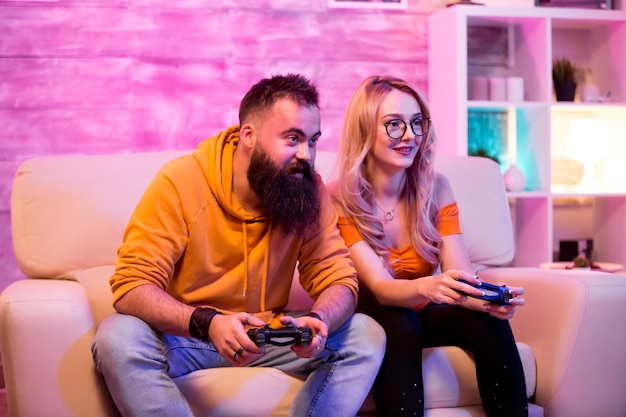 Premium Photo  Boyfriend cheering her beautiul girlfriend while she's playing  online games using wireless controller. room with neon light.