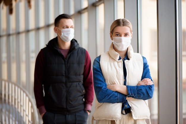 Young man and woman wearing medical masks in an airport lounge