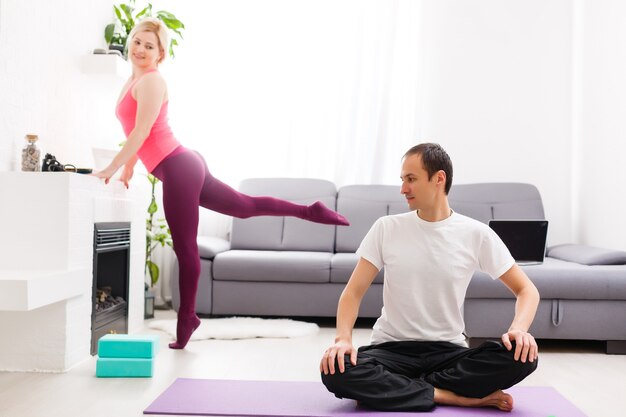 Young man and woman woman doing exercise in the sunny room