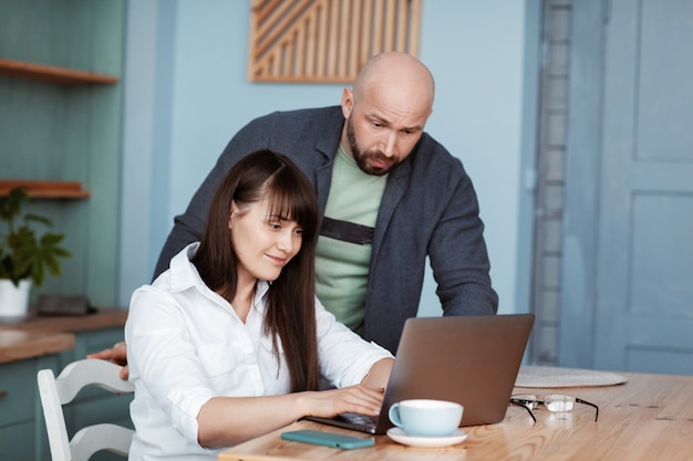 A young man and woman work at home using a laptop