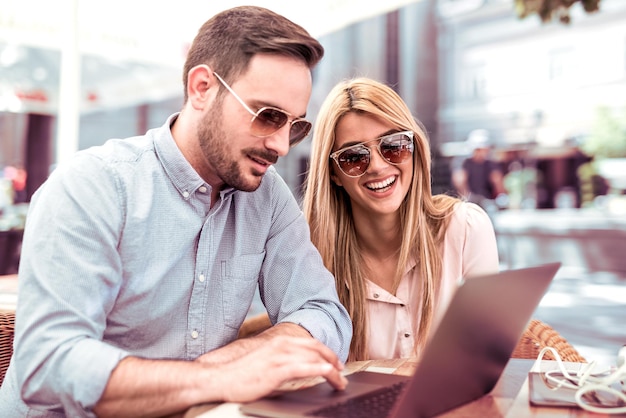 Young man and woman working on laptop in cafe