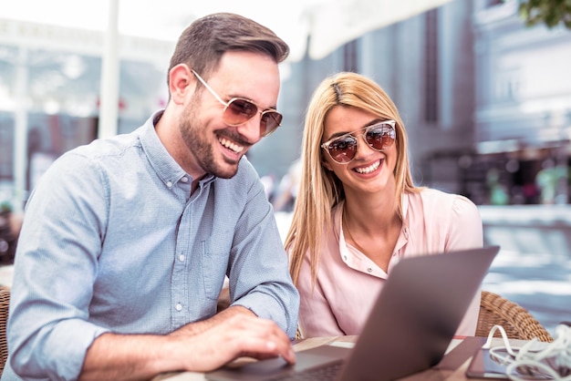 Young man and woman working on laptop in cafe