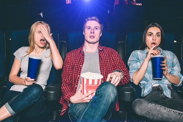 Young man and women are sitting in chairs and watching movie