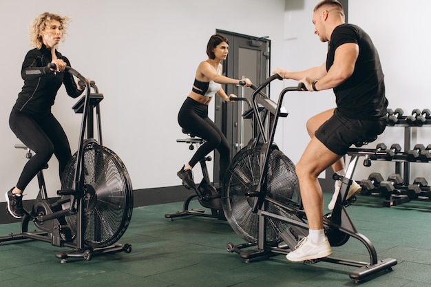 Young man and women using air bike for cardio workout at cross training gym