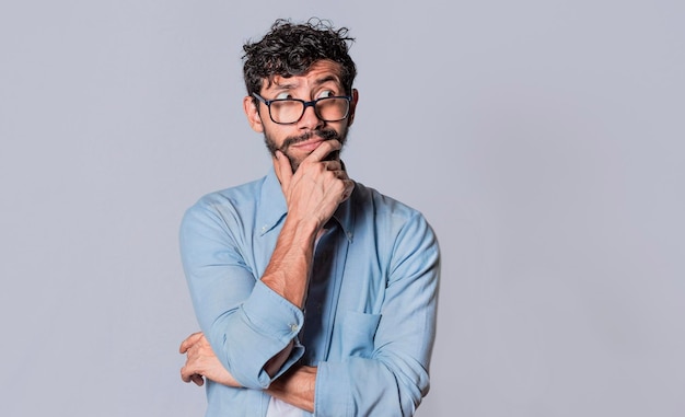 Young man wondering with his hand on his chin on an isolated background a guy thinking with his hand on his chin