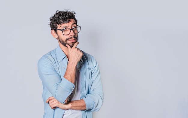 Young man wondering with his hand on his chin on an isolated background a guy thinking with his hand on his chin