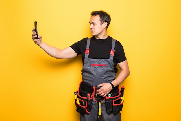 Young man worker with tools belt holding phone