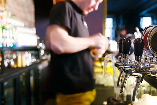 Young man working as a bartender in a nightclub bar